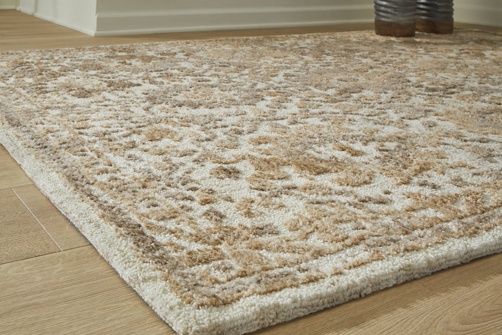 Light brown patterned area rug with dense, distressed floral motifs