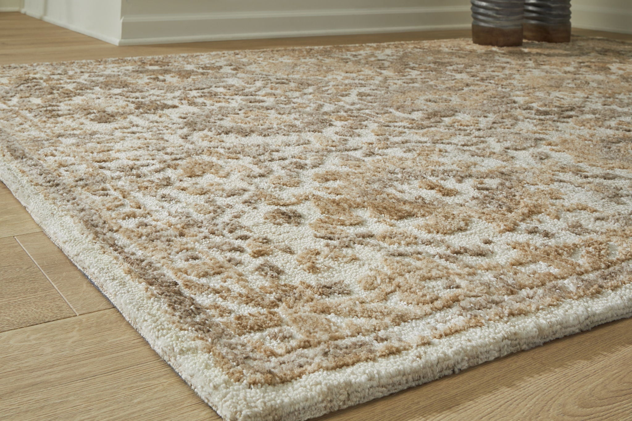 Light brown patterned area rug with dense, distressed floral motifs