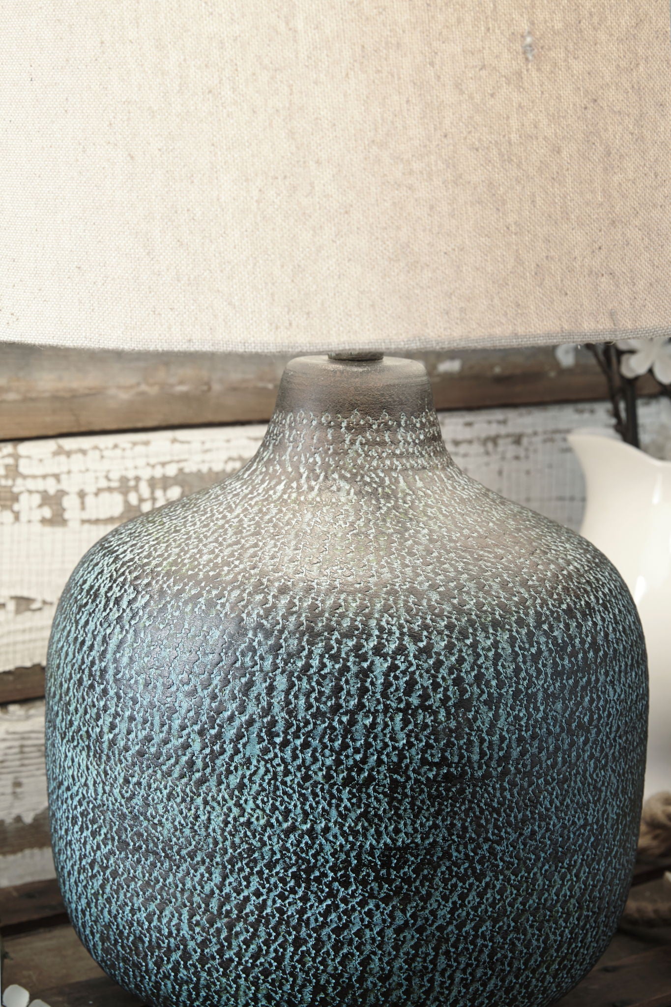 Table lamp with teal speckled metal patina vase base and off-white drum shade