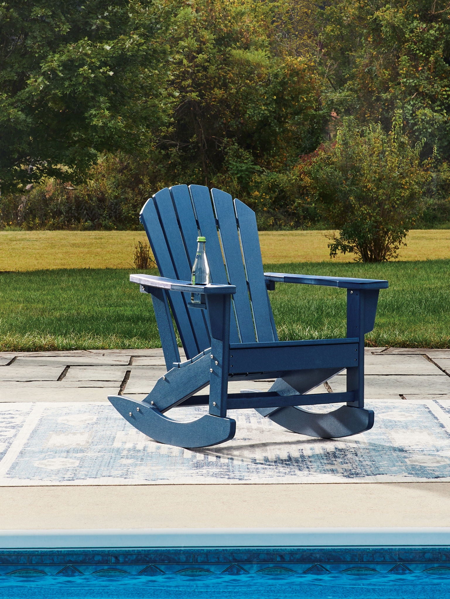 Blue wooden rocking chair with drink holder and slatted back, patio view