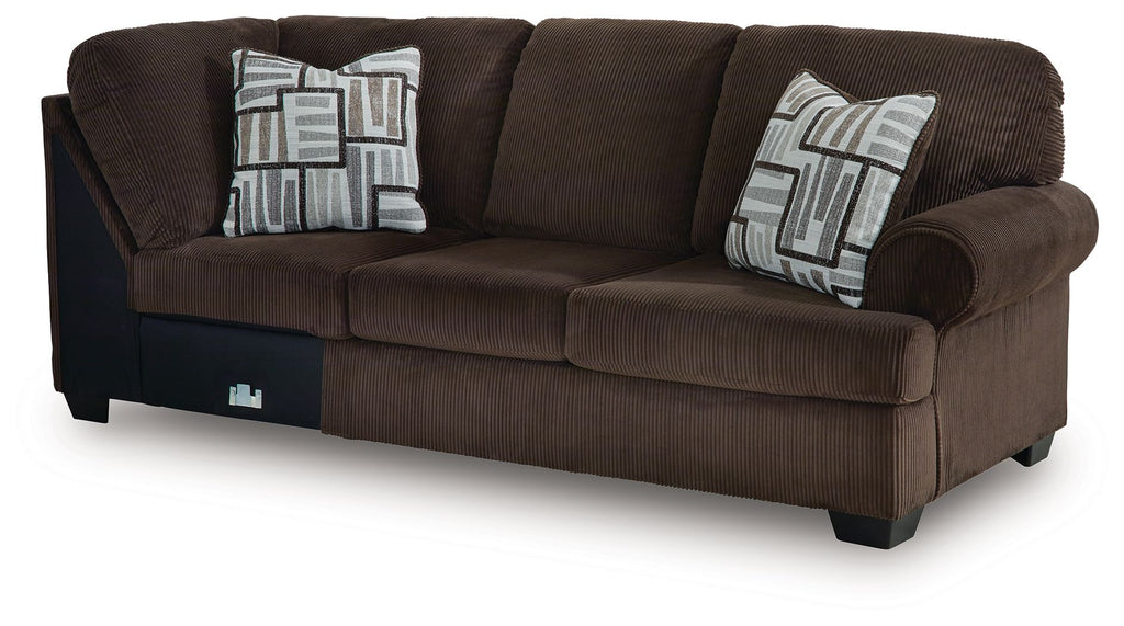 Chocolate-brown upholstered sofa with two geometric patterned throw pillows and armrests