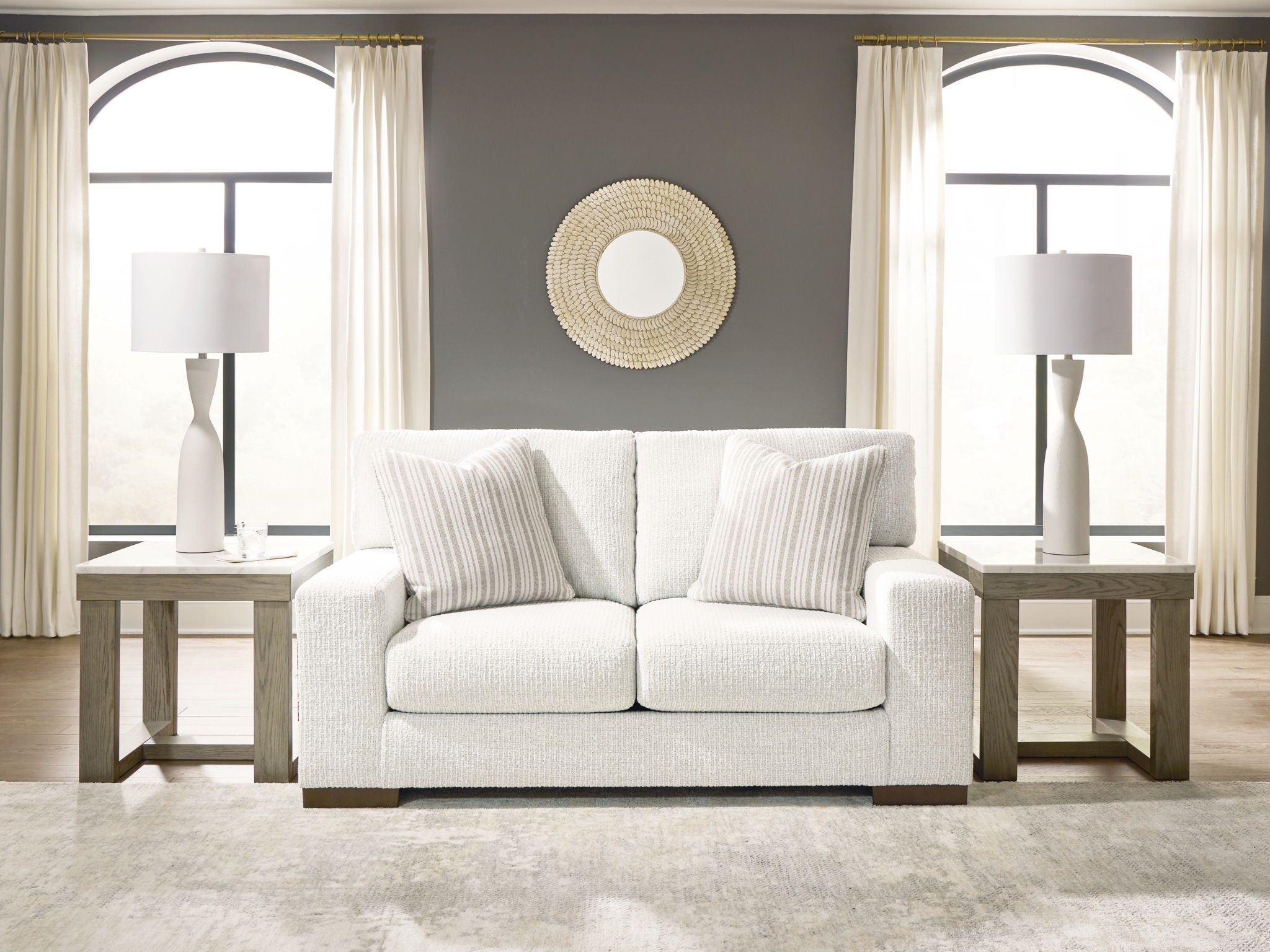 Frosted white loveseat with two seat cushions, striped pillows, and dark base legs