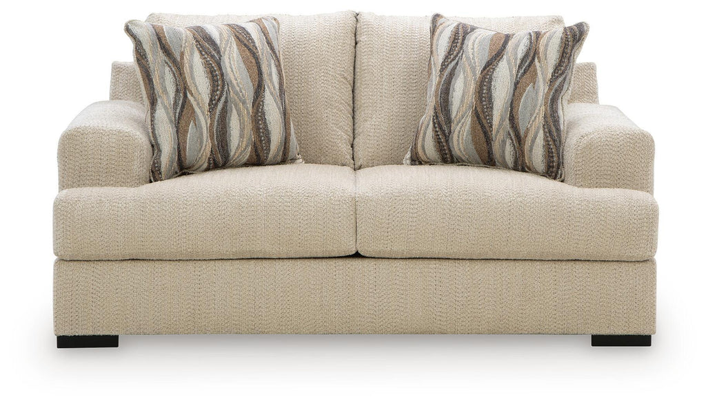 Beige loveseat with tufted back cushions and two striped throw pillows