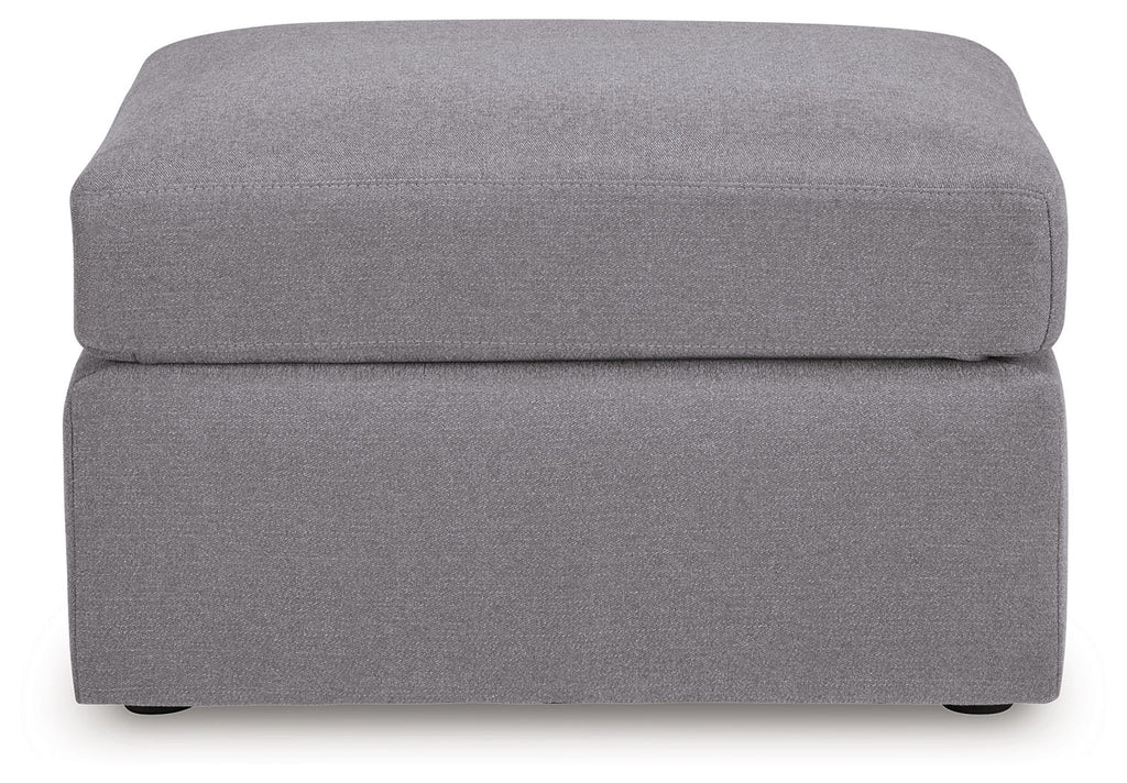 Gray accent ottoman with cushioned top and square base, low dark legs.