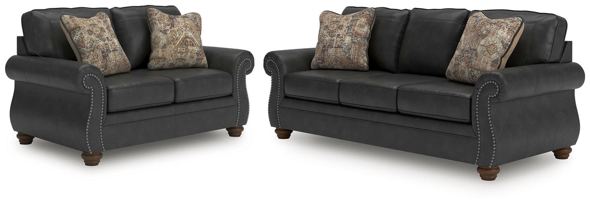 Dark gray sofa set with patterned accent pillows and studded trim on rolled arms