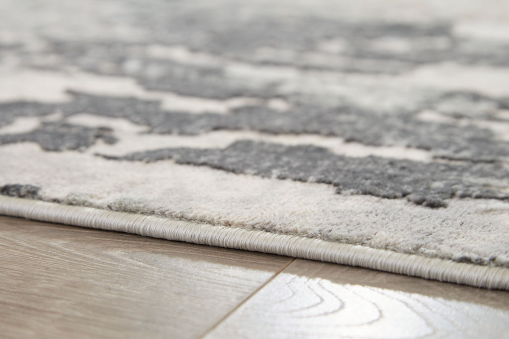 Gray abstract rug border edge with stitched fringe and low-pile texture