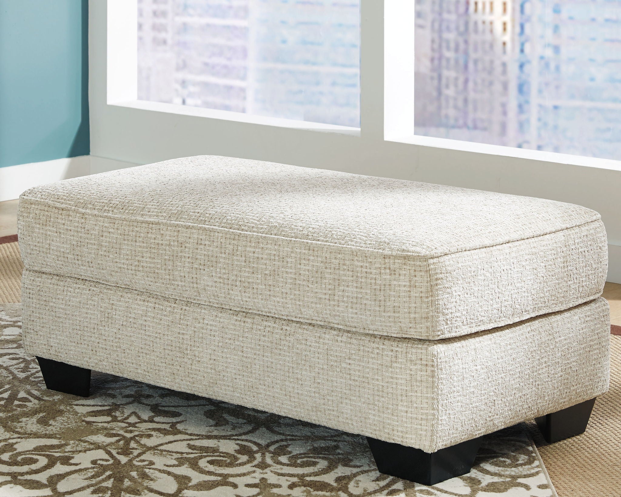 Rectangular ottoman with light beige upholstery and black legs