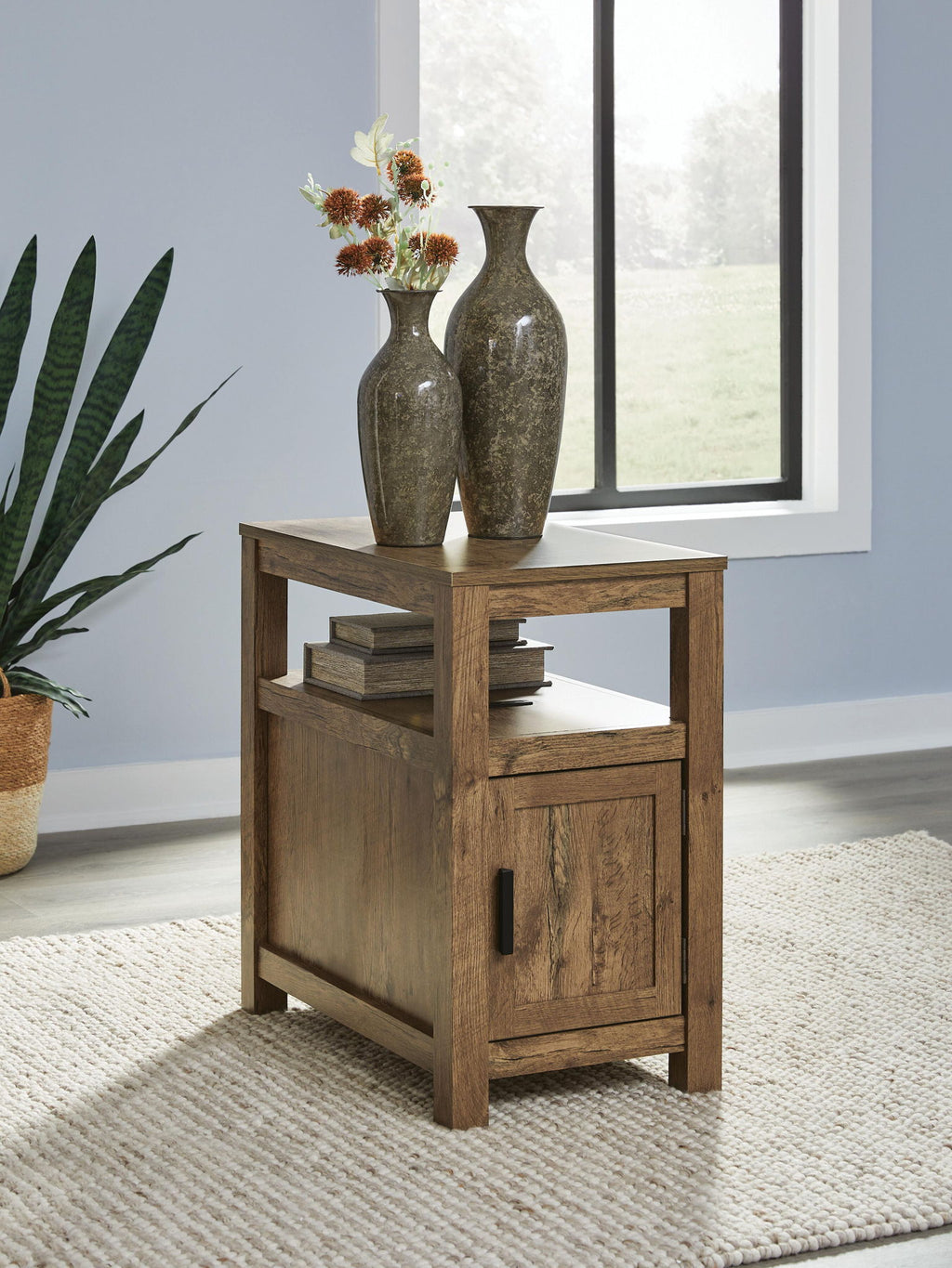 Chair side end table in rustic light brown wood with open shelf and cabinet door with black pull