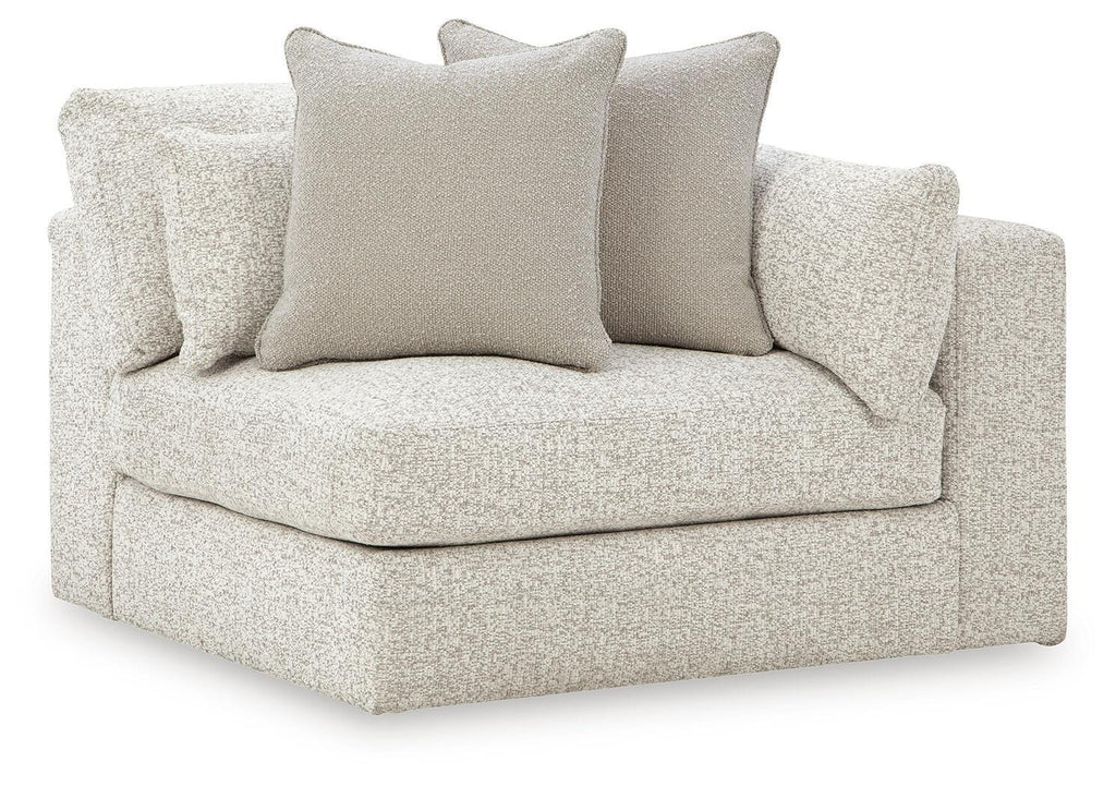 Light grey corner accent chair with boxed armrests and three scatter cushions