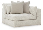 Light grey corner accent chair with boxed armrests and three scatter cushions