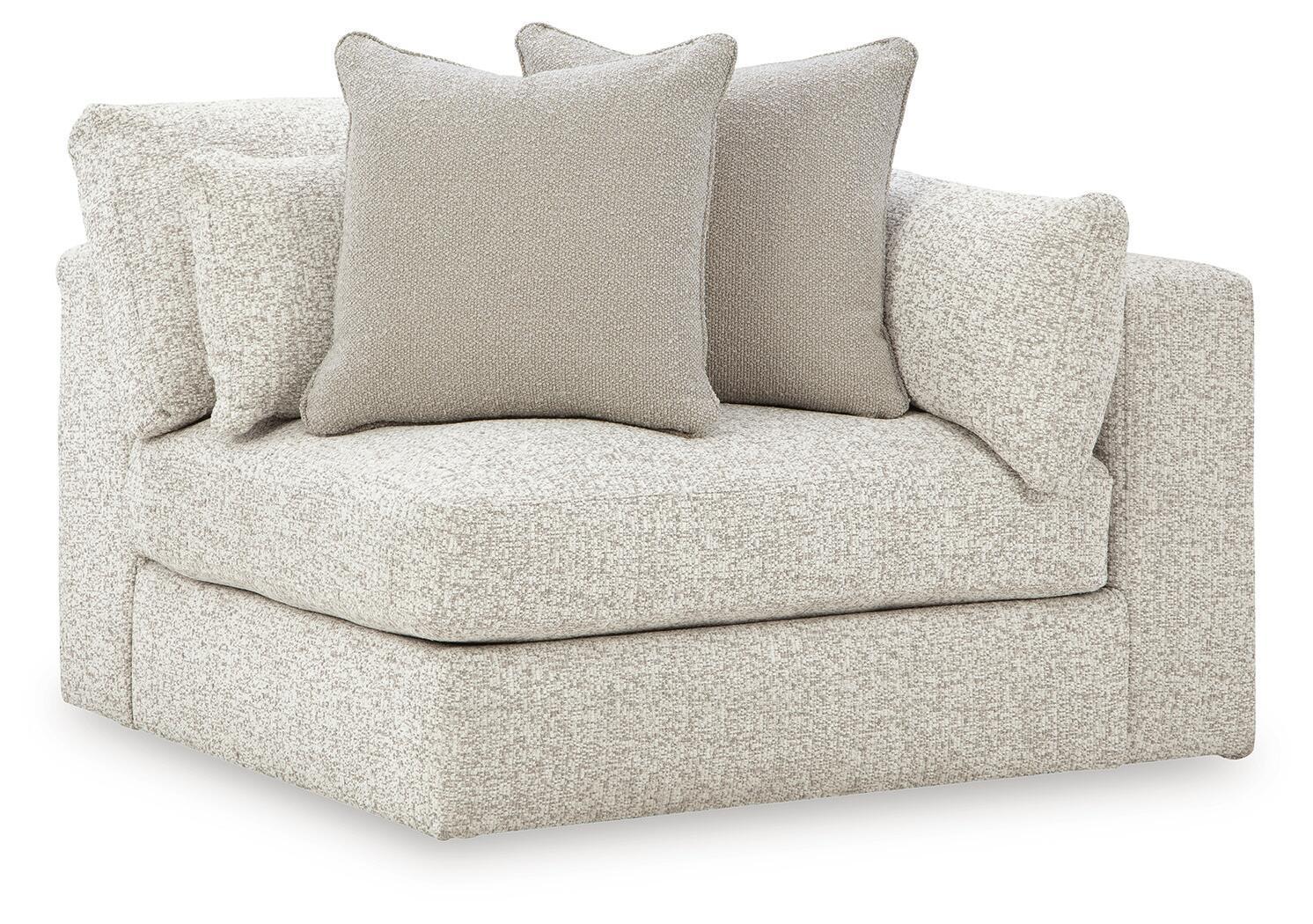 Light grey corner accent chair with boxed armrests and three scatter cushions