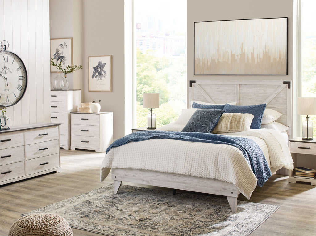 White panel bed with blue quilt and pillows, featuring dark metal legs