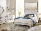 White panel bed with blue quilt and pillows, featuring dark metal legs