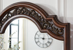 Brown arched mirror frame close-up with ornate scrolling carvings