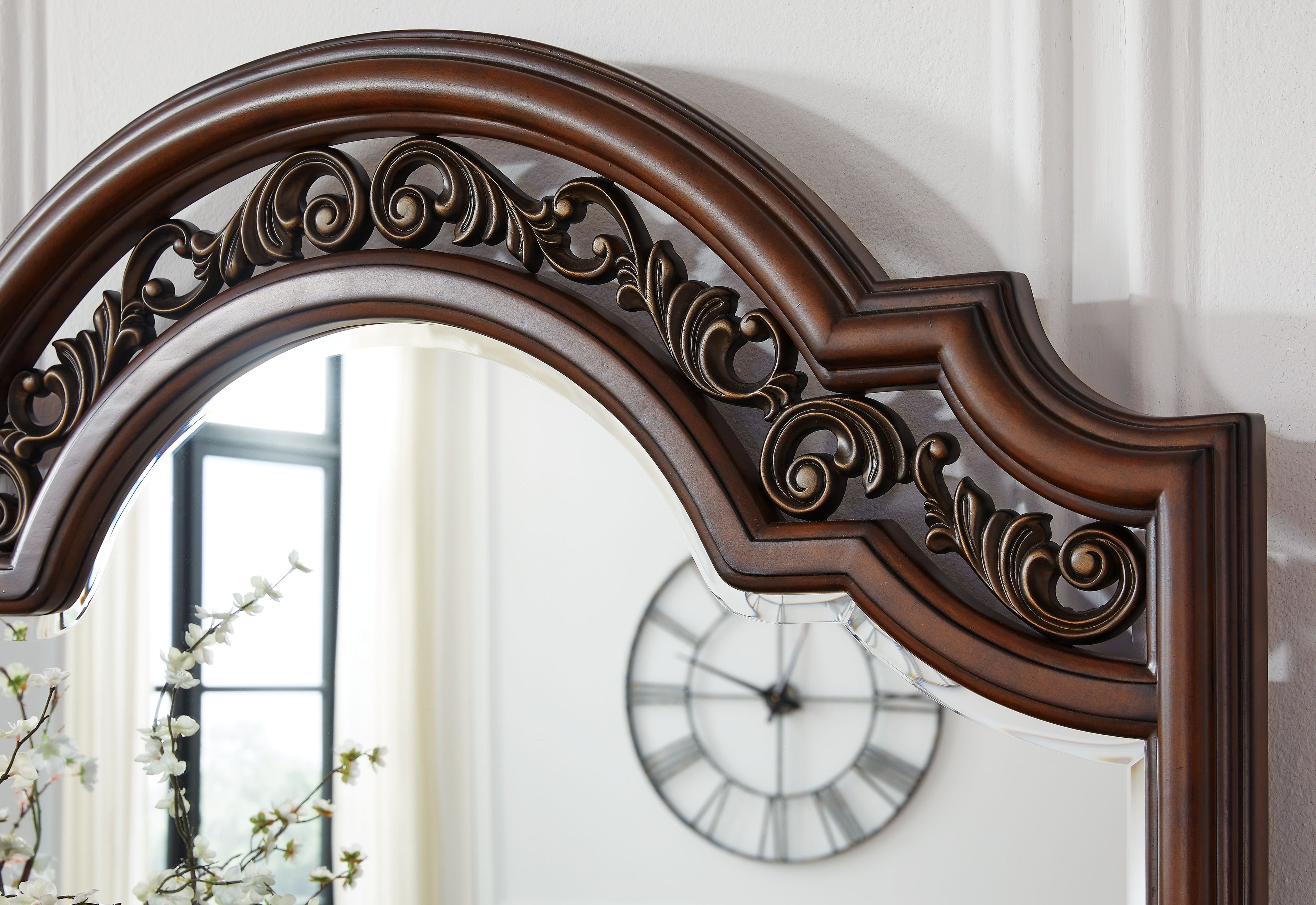 Brown arched mirror frame close-up with ornate scrolling carvings