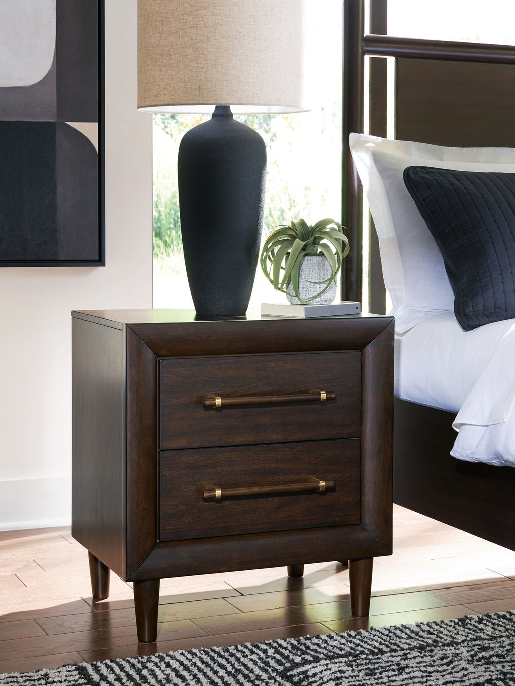 Two-drawer night stand in dark wood with two brass bar pulls and tapered legs