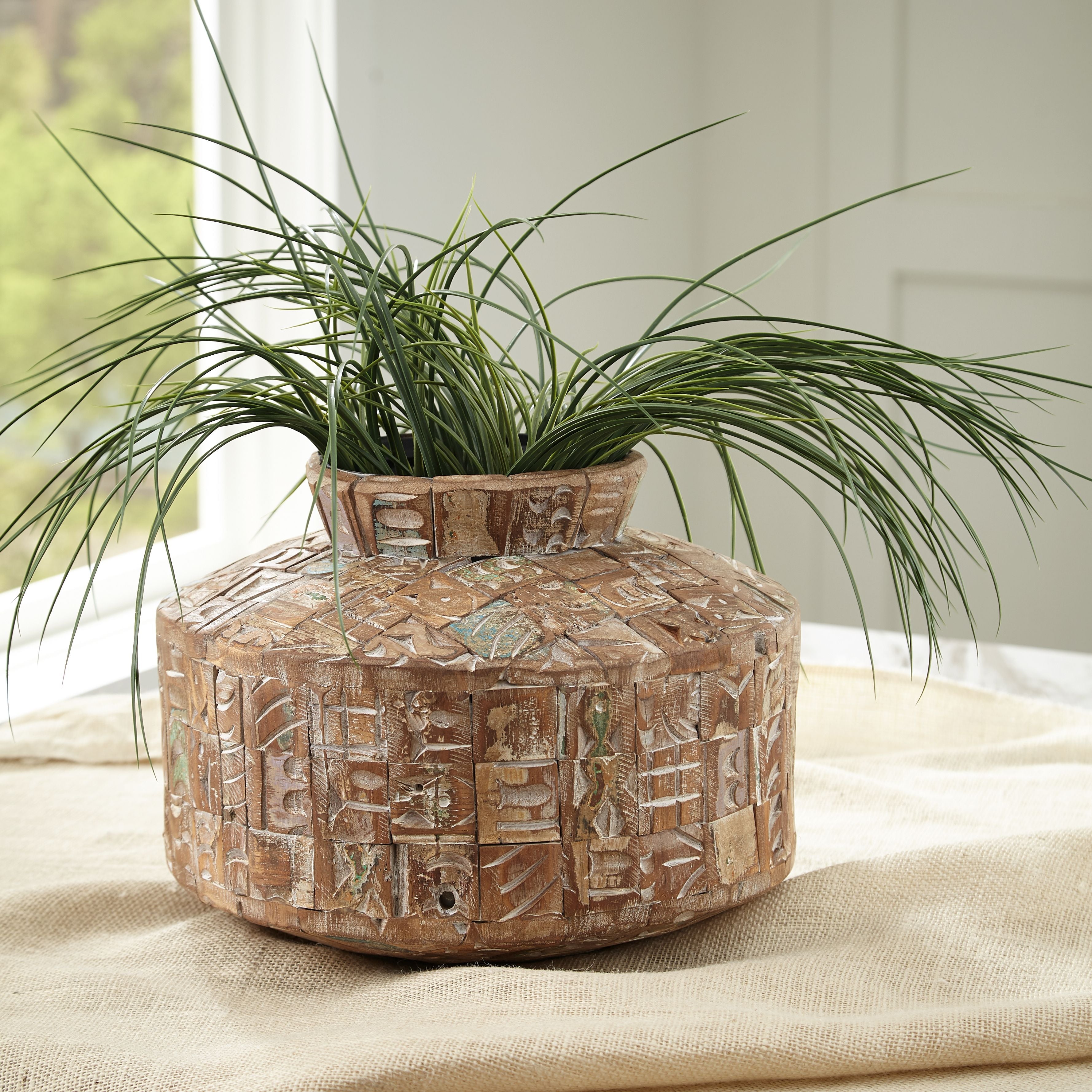 Textured ceramic vase with carved block pattern and round opening, brown with teal highlights.