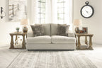Beige fabric loveseat with three patterned throw pillows