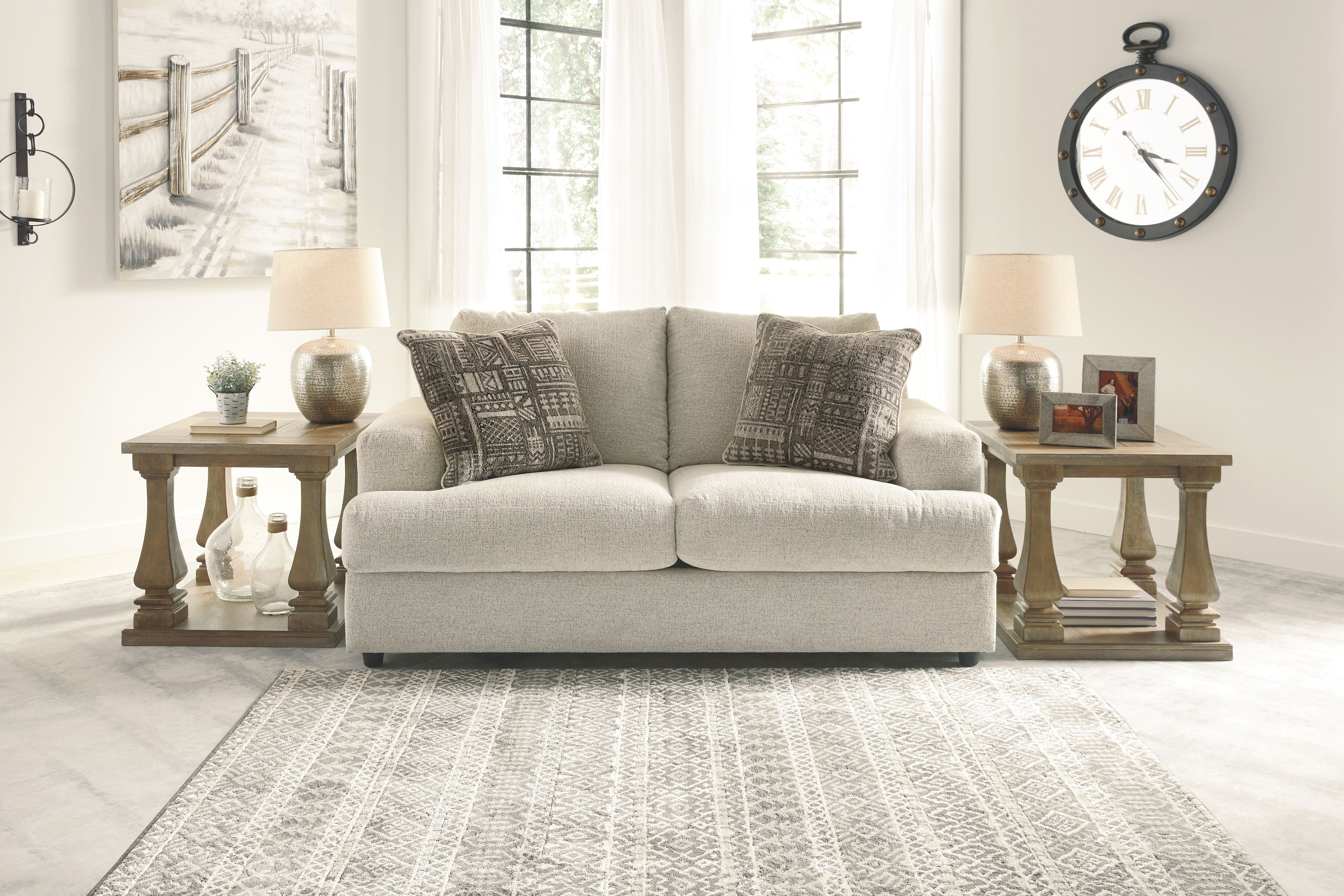 Beige fabric loveseat with three patterned throw pillows