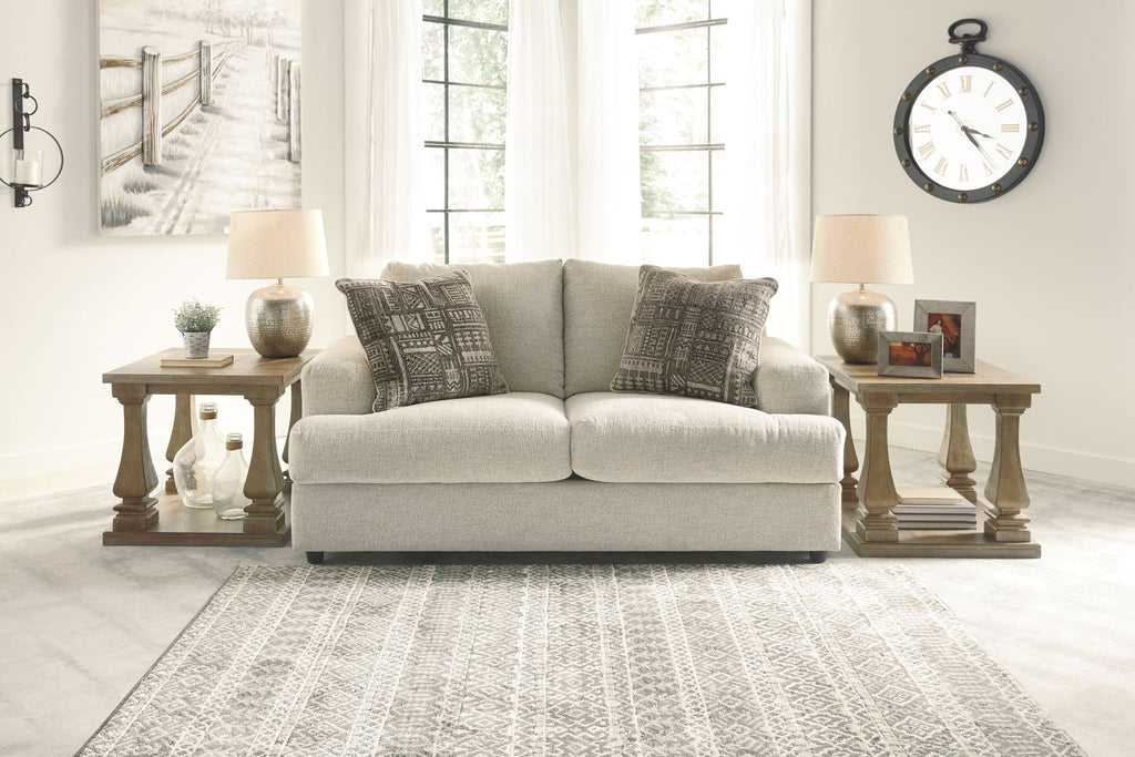 Stone upholstered loveseat with two patterned accent pillows