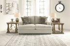 Stone upholstered loveseat with two patterned accent pillows