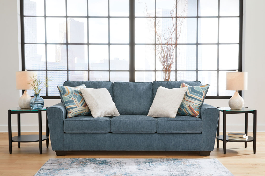 Blue fabric sofa with three seat cushions and patterned accent pillows