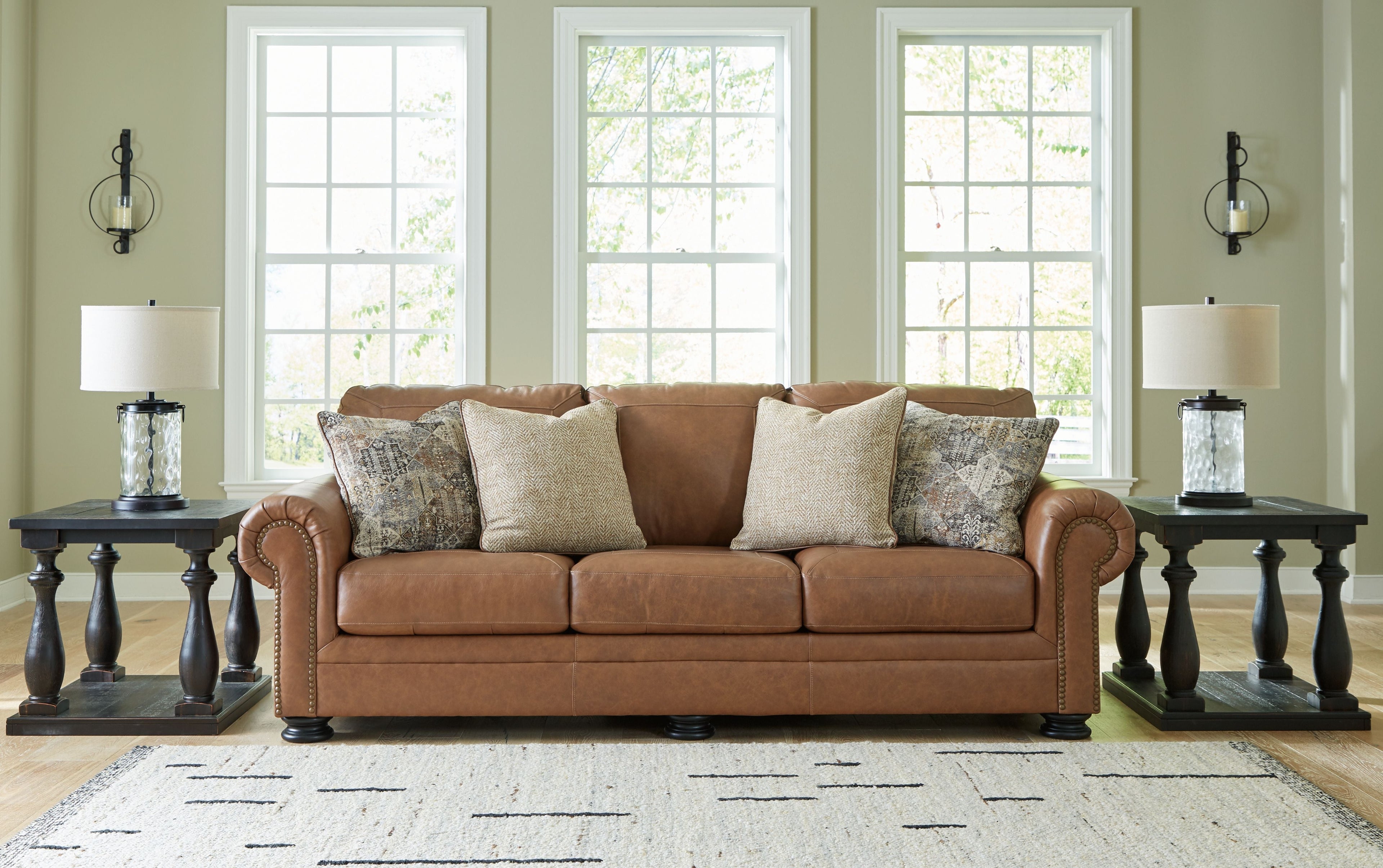 Caramel leather sofa with three seat cushions and patterned accent pillows
