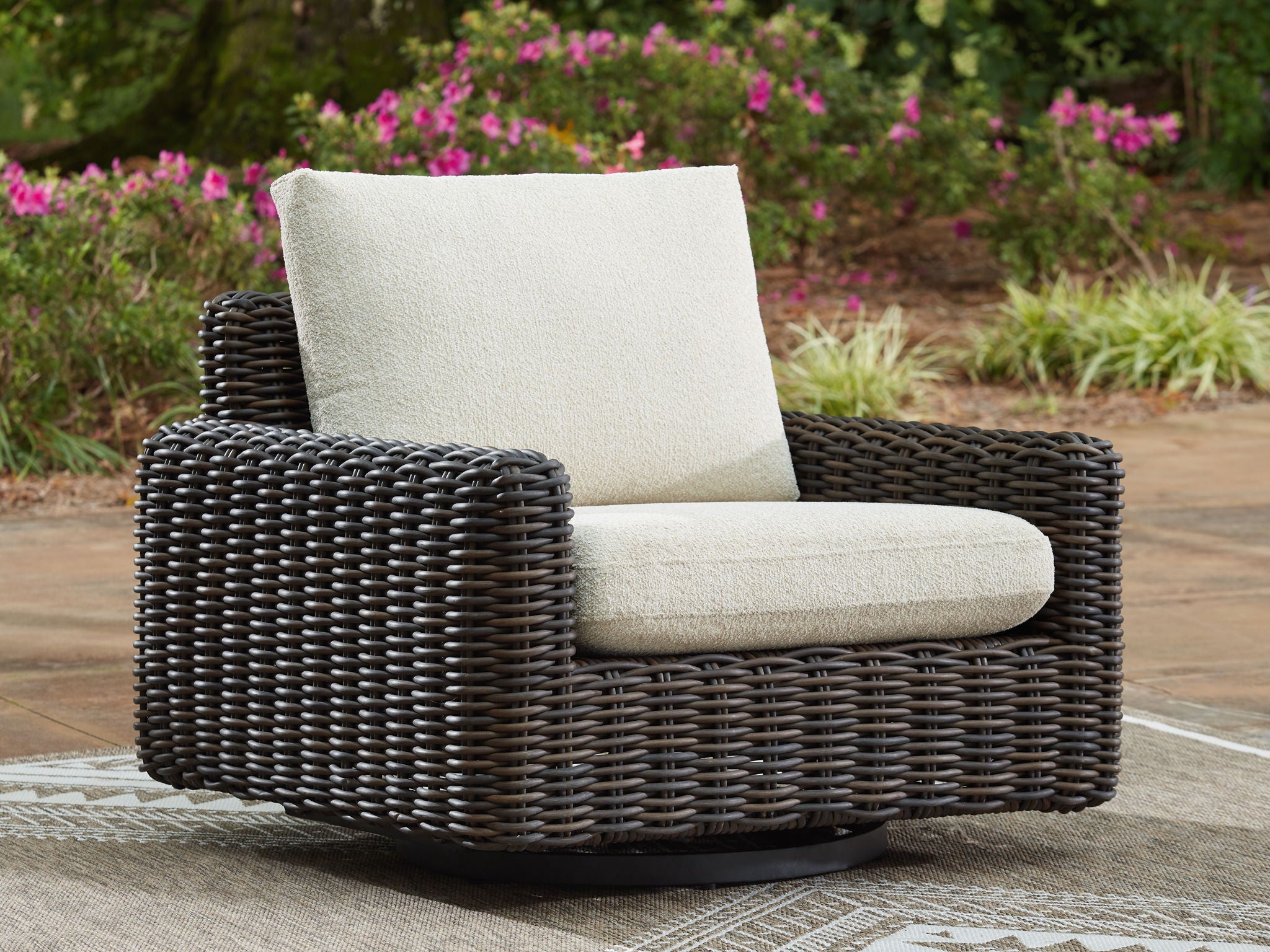Swivel glider lounge chair with dark brown wicker and beige upholstered seat