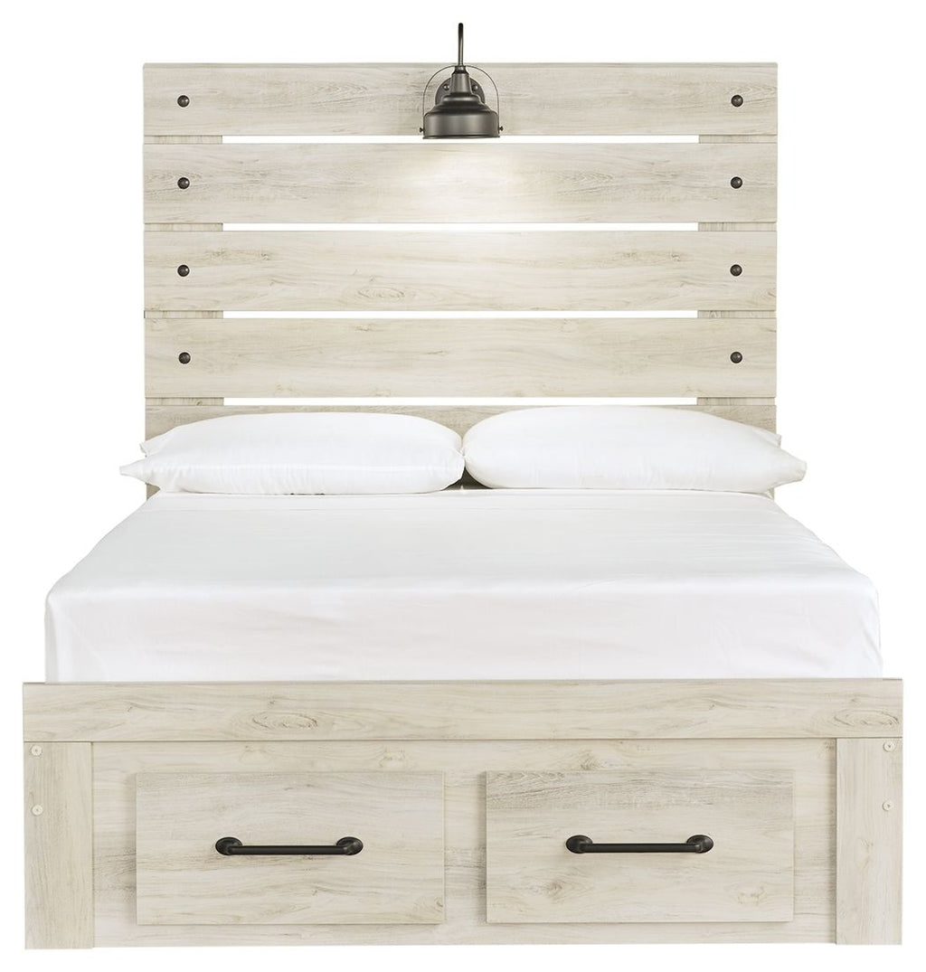 Light wood panel bed with two front drawers; white bedding and two black bedside lamps on headboard