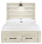 Light wood panel bed with two front drawers; white bedding and two black bedside lamps on headboard