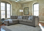 Slate gray sectional sofa with chaise, tufted cushions and patterned throw pillows.