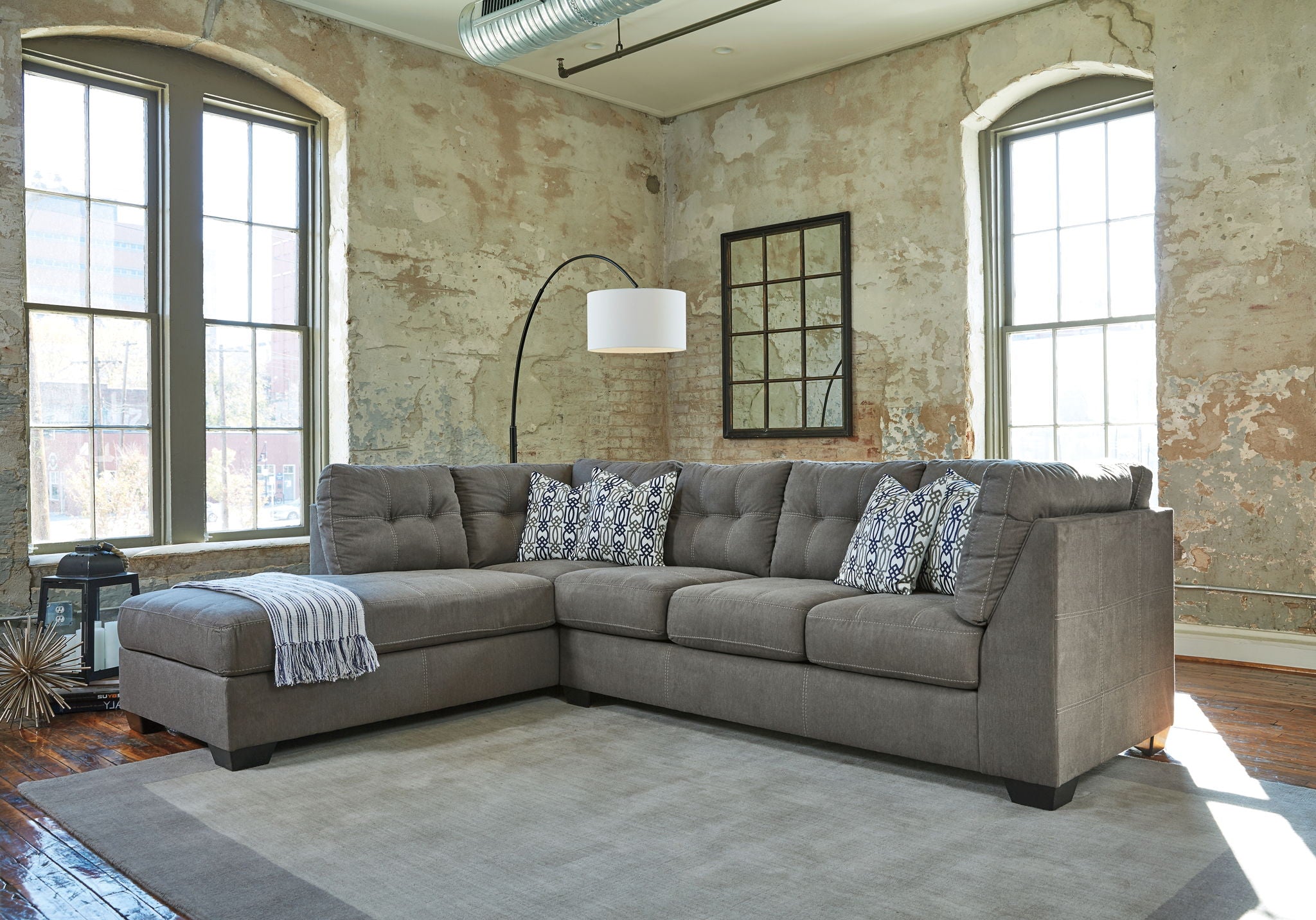 Slate gray sectional sofa with chaise, tufted cushions and patterned throw pillows.