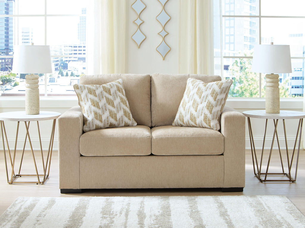 Beige upholstered loveseat with two geometric throw pillows