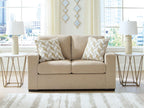 Beige upholstered loveseat with two geometric throw pillows
