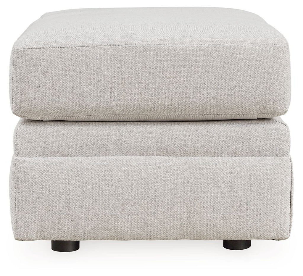 Light beige upholstered ottoman, rounded lid on two-step base with visible feet