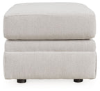 Light beige upholstered ottoman, rounded lid on two-step base with visible feet