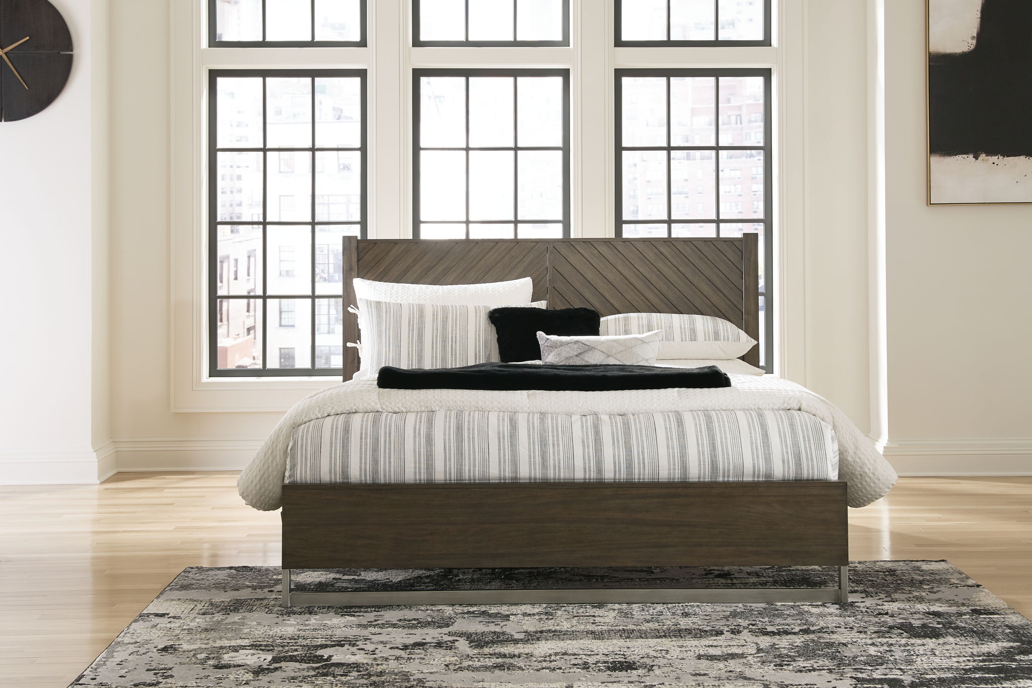 King panel bed with dark gray-brown headboard, striped duvet, and pillows