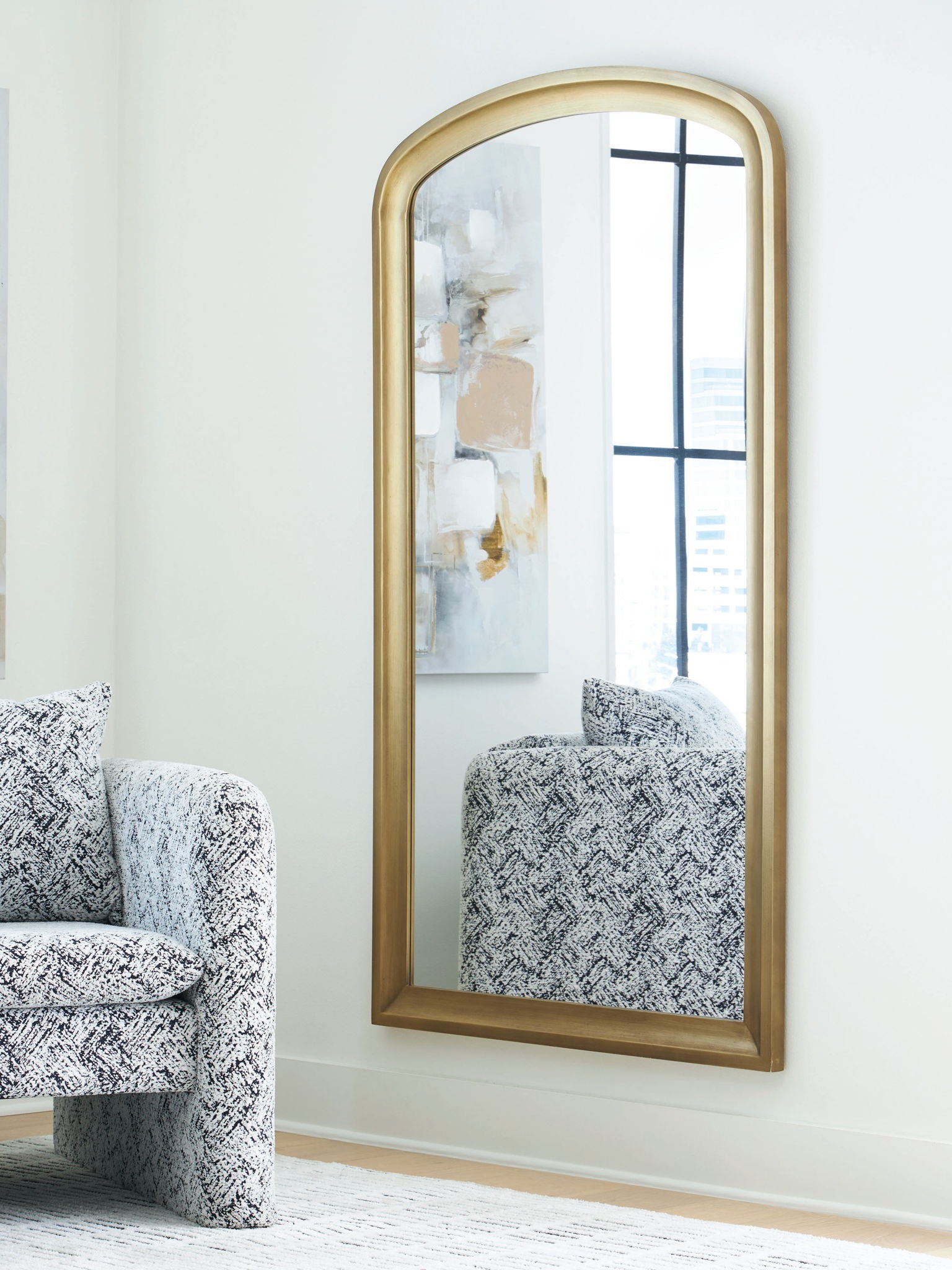 Arched floor mirror with slim gold frame and reflective glass panel