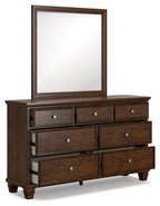 Brown dresser with tall framed mirror and drawer fronts, round metal knobs.