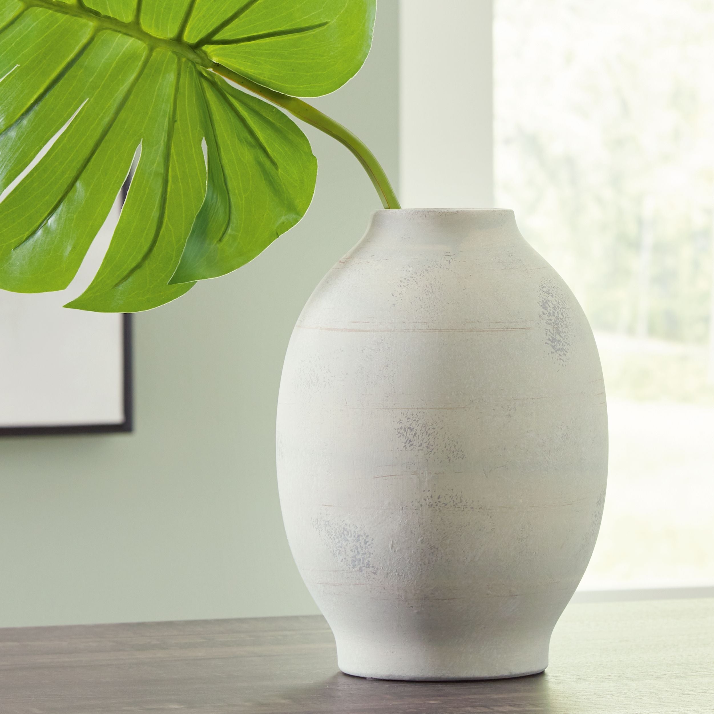 Cream ceramic vase with rounded shape and flared rim, speckled glaze texture.