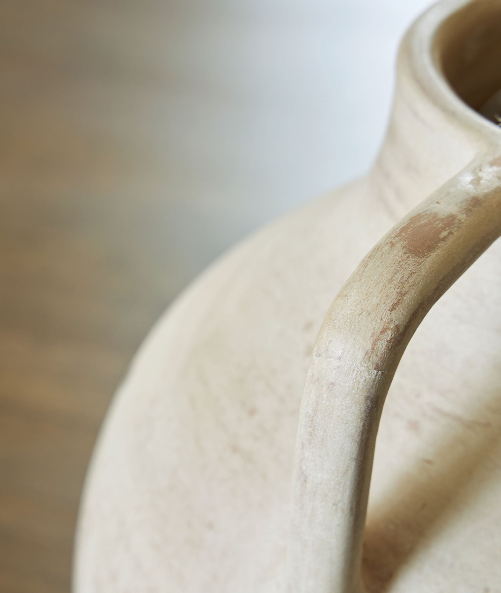 Beige ceramic vase close-up of curved neck and rim texture
