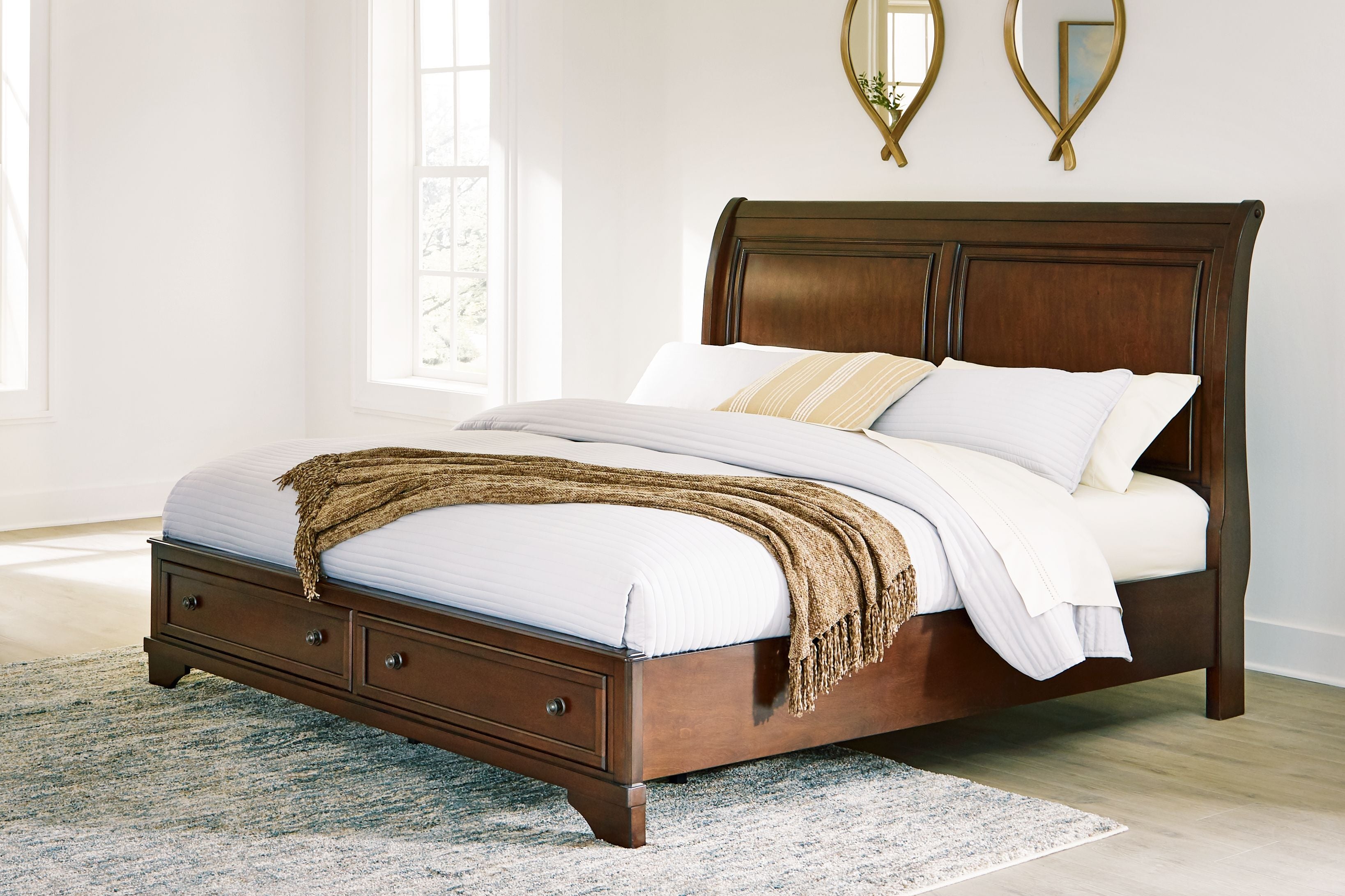 Brown king storage bed with paneled headboard and two foot drawers, shown with pillows