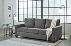 Dark gray sofa with seat cushions and beige throw draped over arm