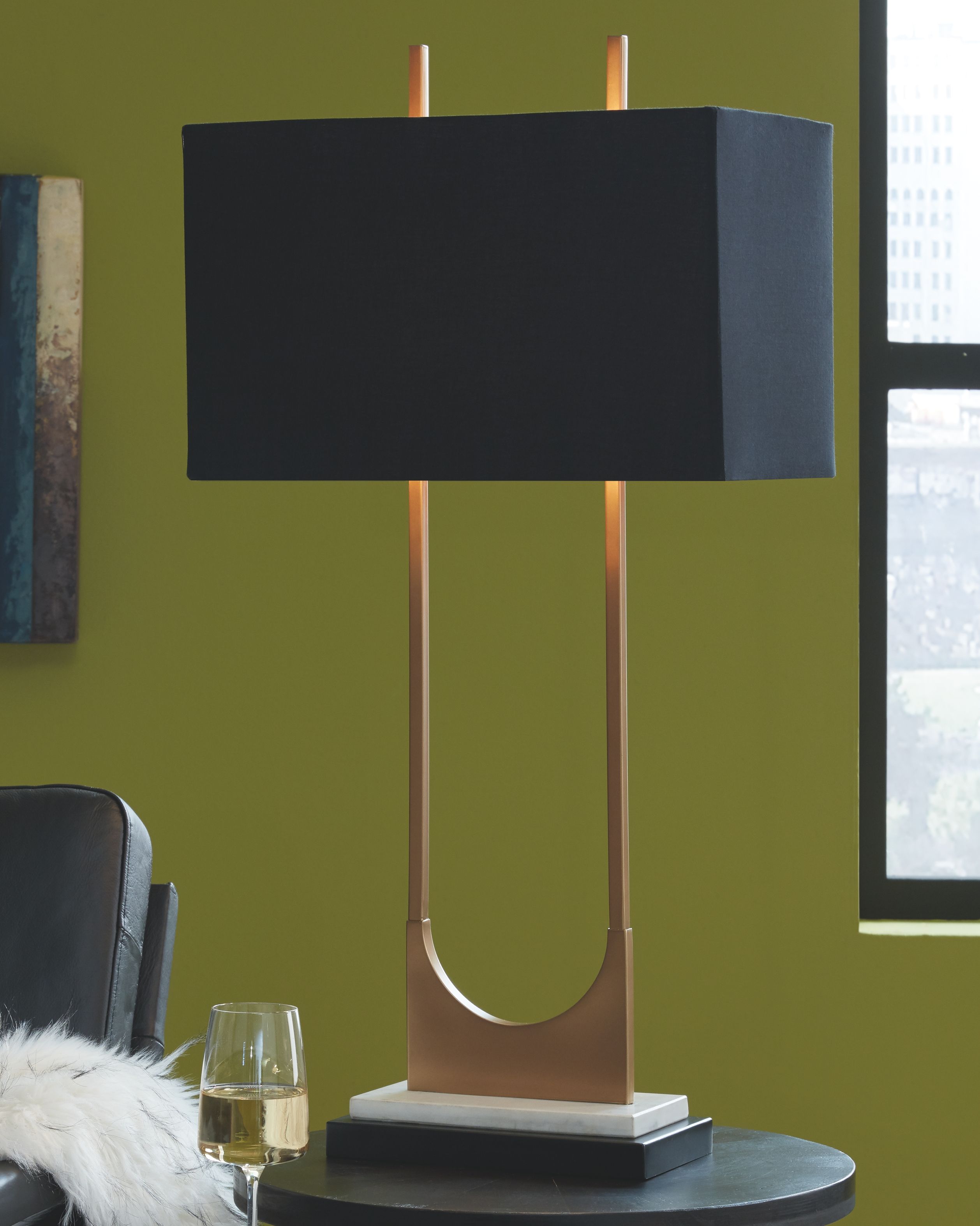 Brass metal table lamp with black shade and curved U frame on gray base