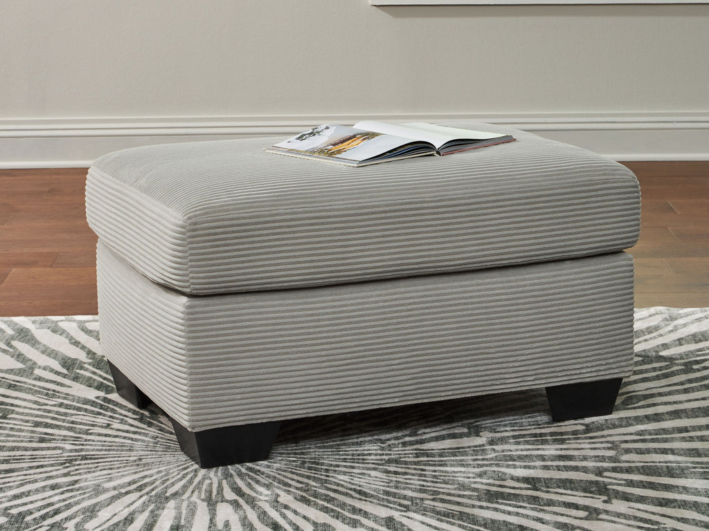 Light gray upholstered ottoman with rounded lid, ribbed upholstery, and dark legs