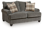 Gray upholstered loveseat with tufted arms and two plaid throw pillows