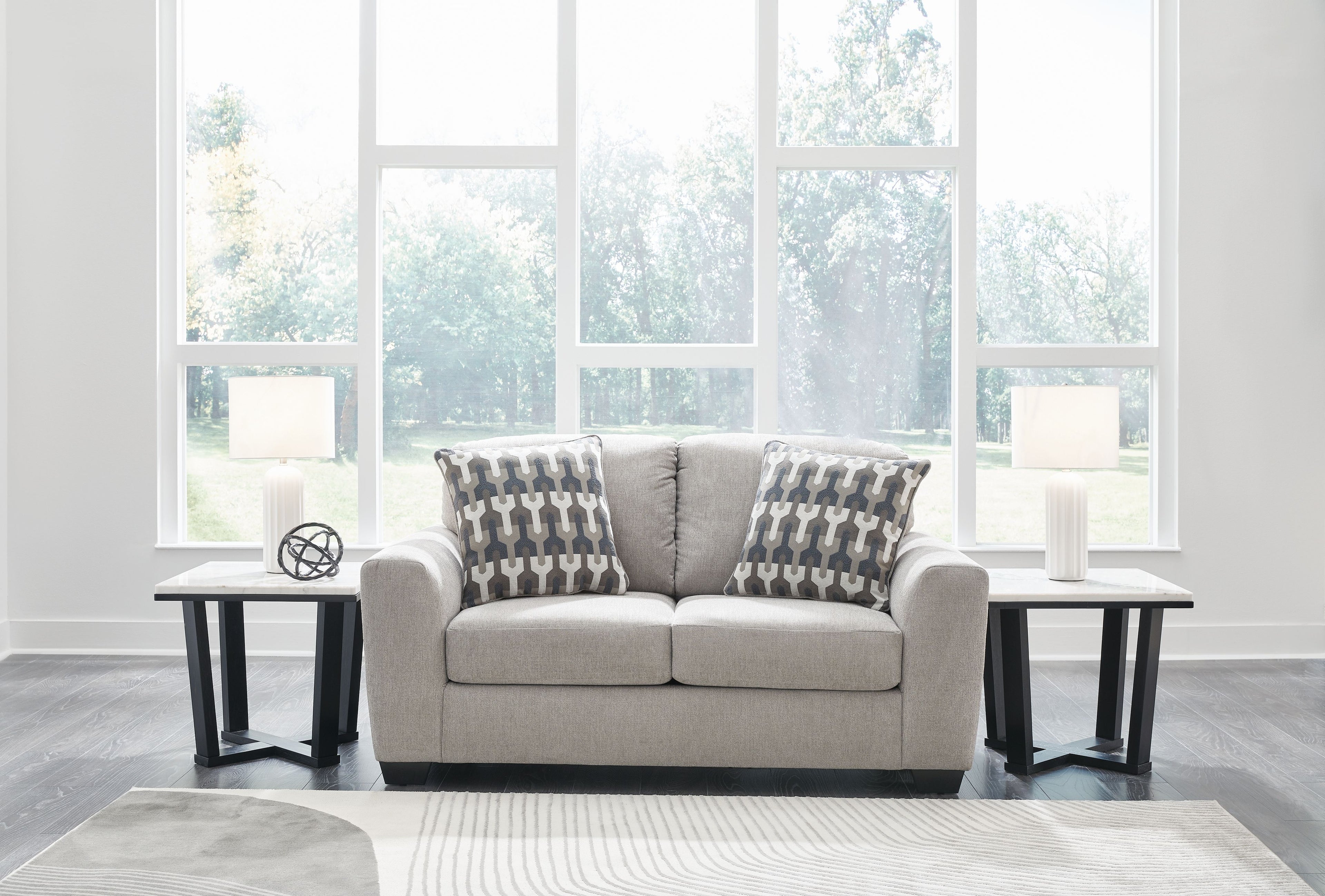 Gray flannel loveseat with two geometric-pattern throw pillows