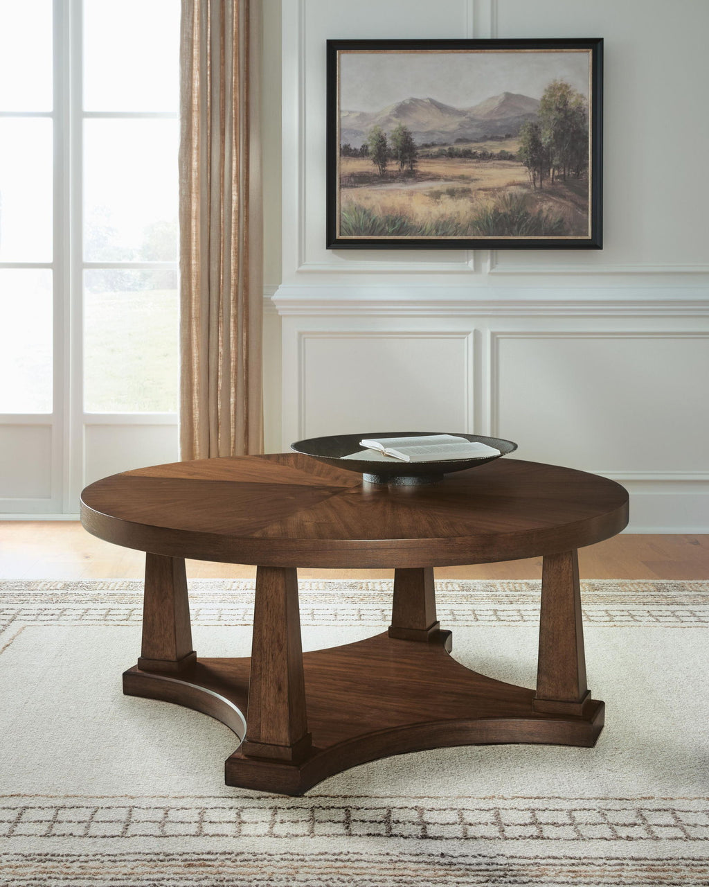 Round wooden coffee table in light brown with pedestal base, front three-quarter view