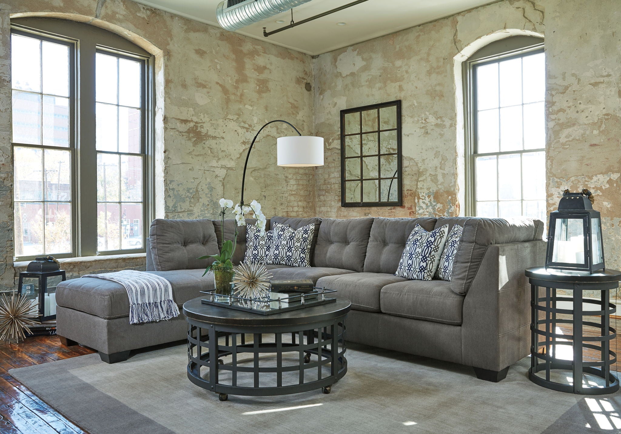 Slate gray corner sectional sofa with chaise, tufted seat cushions and patterned pillows.