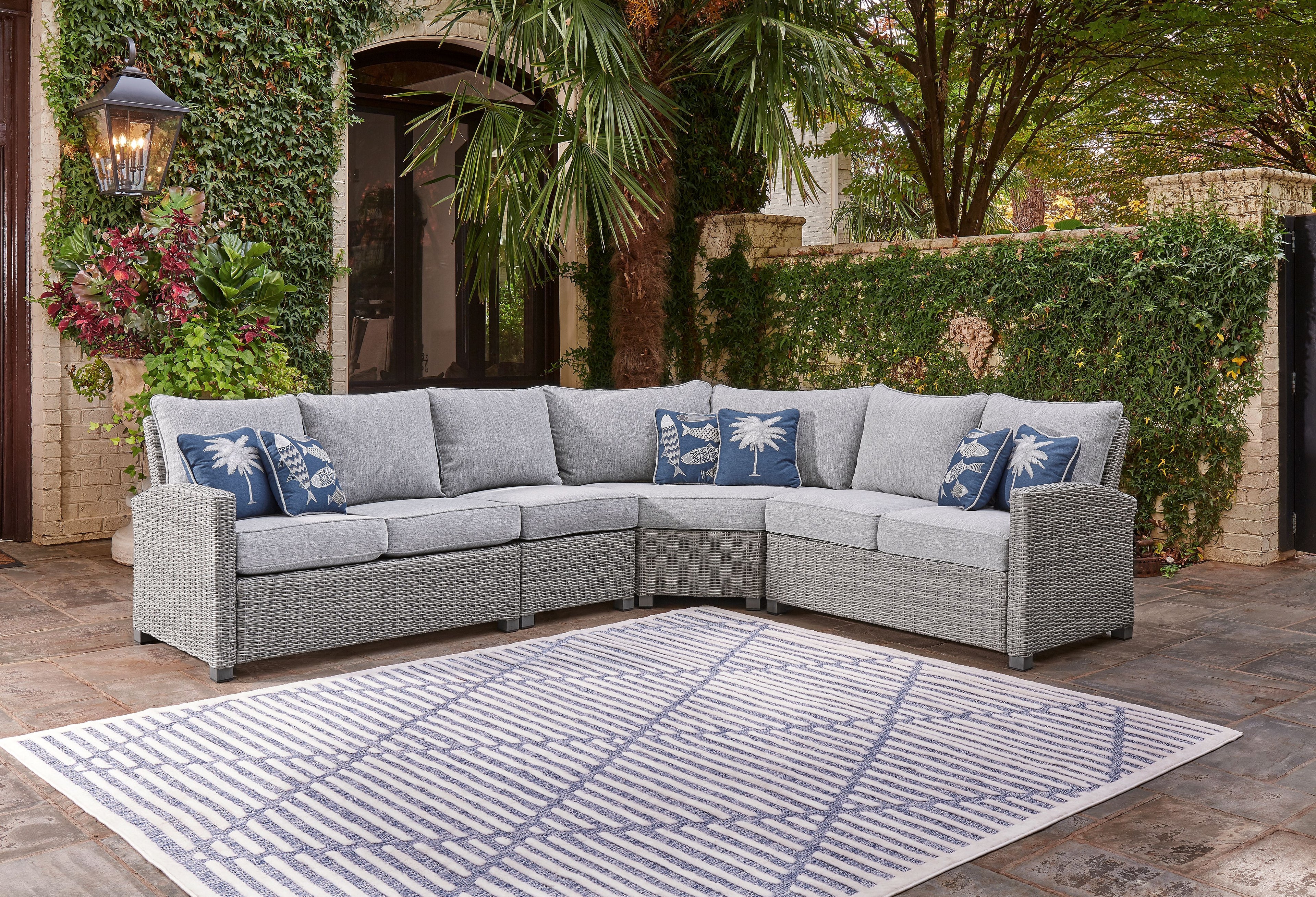 Light gray outdoor sectional sofa with blue patterned throw pillows